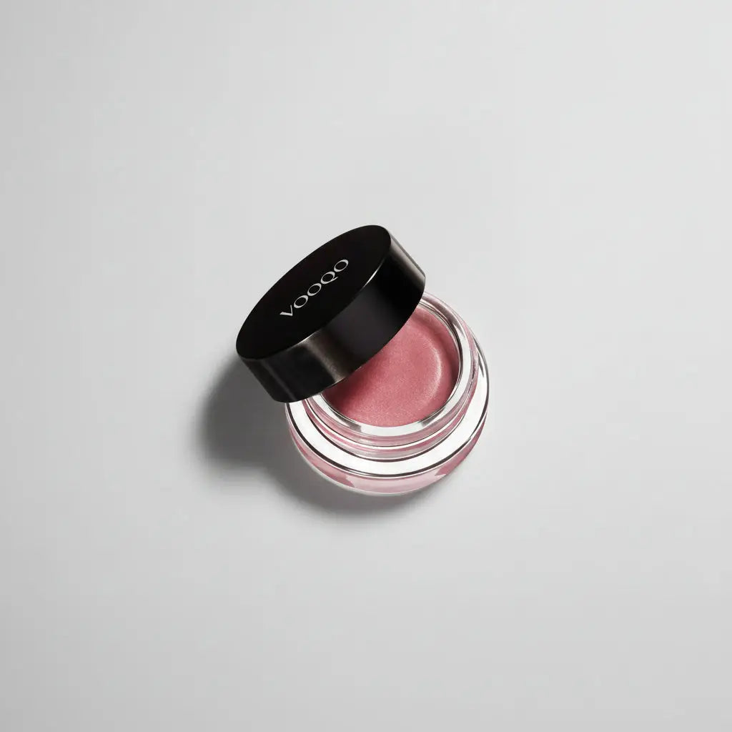 Un pot negru elegant cu capac ce conține un cream blush lip balm roz fin și neted